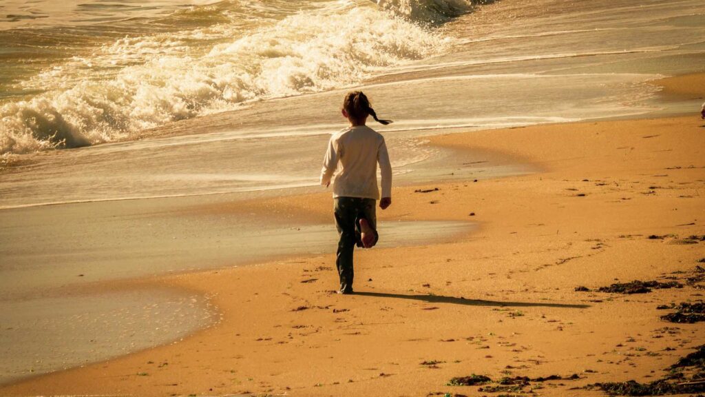 A child walking alone along the shoreline, illustrating the risks of Wandering near water because of autism and elopement behaviors
