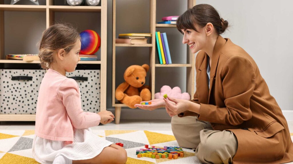 Therapist working with a young child using colorful blocks during an autism assessment, representing how profound autism is diagnosed through observation and interaction.