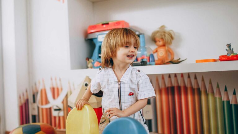 Young child playing in a colorful room, representing the experiences and support needs of children with profound autism and severe autism.