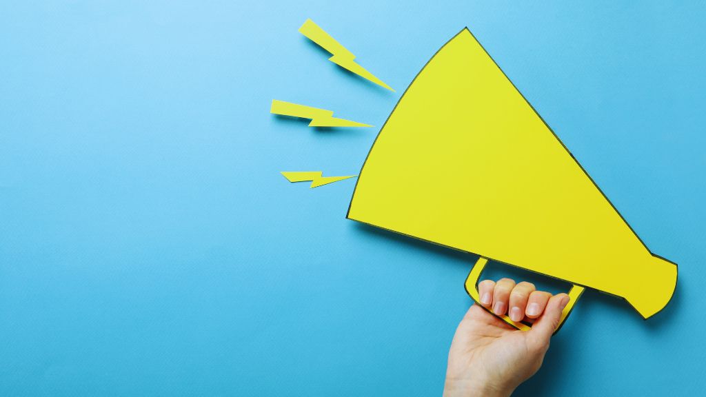 Bright yellow megaphone held by a hand, with sound waves symbolized by lightning bolts, set against a blue background. Represents communication of key autism-related updates, including acetaminophen (Tylenol) use during pregnancy, autism research, and evidence-based therapies like ABA. Keywords: acetaminophen, autism, Tylenol, pregnancy, leucovorin, evidence-based.